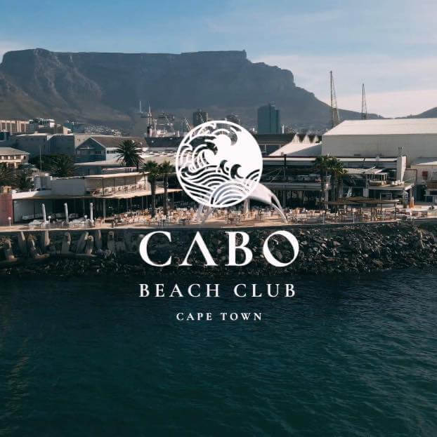 Background view of Table Mountain from the V&A Waterfront with the words Cabo Beach Club Cape Town with the logo on the foreground